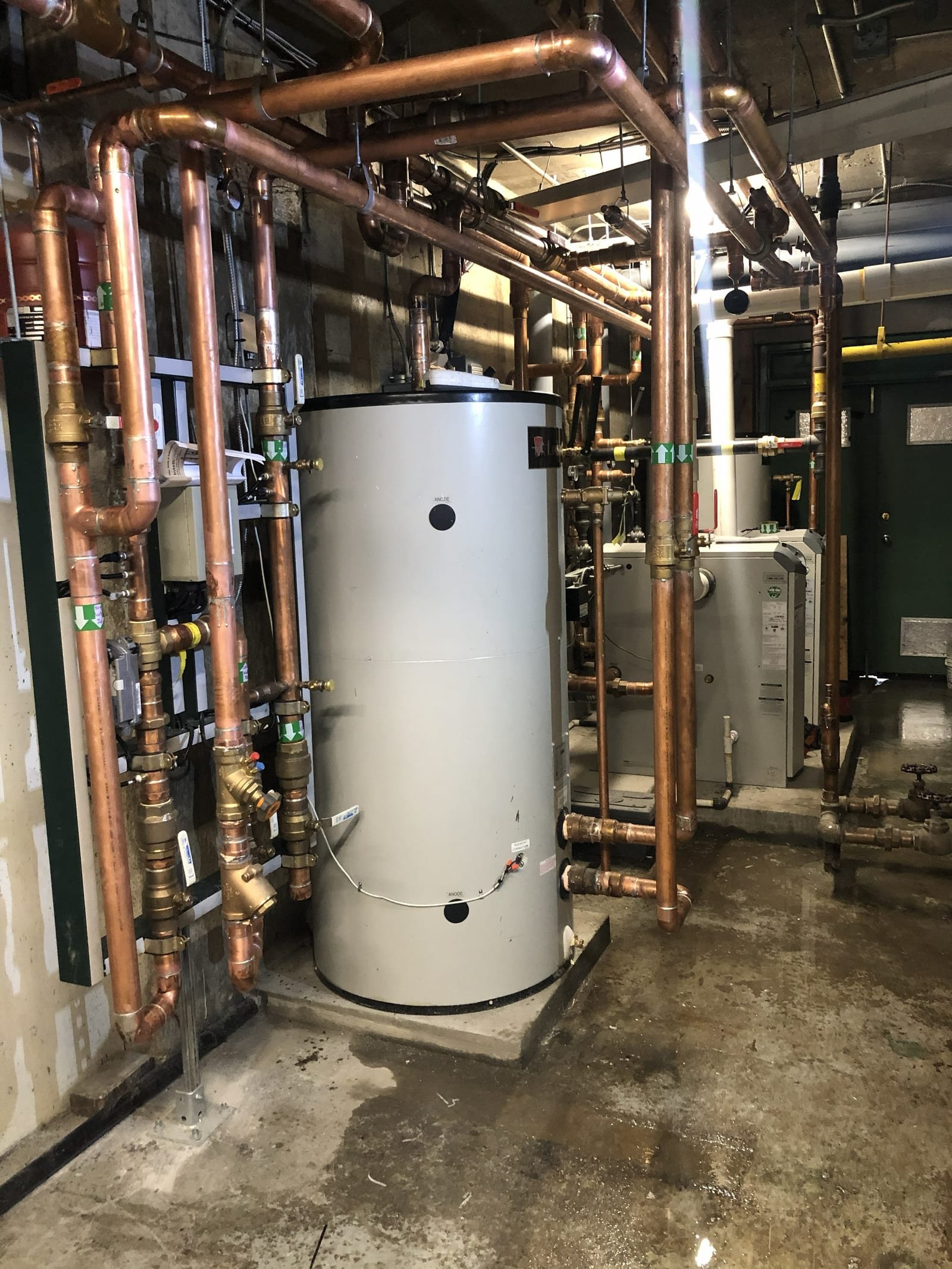 Commercial mechanical-room tank surrounded by copper piping